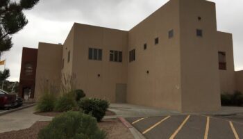 Exterior view of tan stucco behavioral health facility with multi-level design, landscaping, and parking area