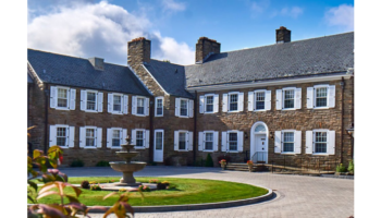 Exterior view of stone building with central courtyard featuring circular fountain and manicured landscaping