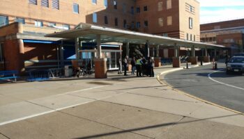 Exterior covered entrance with modern canopy structure, glass doors, and brick building facade