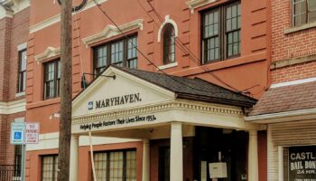 Exterior view of brick treatment facility entrance with Maryhaven logo, mission statement signage, covered portico with columns, and street-level accessibility
