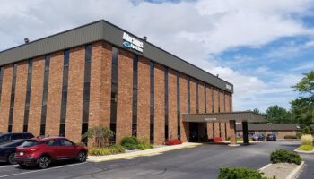 Exterior view of brick treatment facility building with parking area, landscaping, and main entrance with covered entry