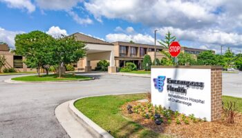 Exterior view of Encompass Health Rehabilitation Hospital with main entrance, sign, landscaped grounds, and parking area