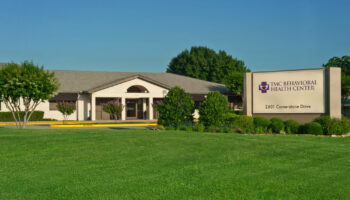 Exterior view of TMC Behavioral Health Center showing main entrance, landscaped grounds, facility signage, and clear blue sky