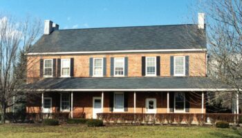 Exterior of brick treatment facility with two-story colonial architecture, front porch, landscaped grounds, and manicured lawn area