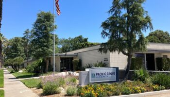 Exterior front entrance of Pacific Grove Hospital showing main sign, landscaped grounds with flowering plants, and facility building