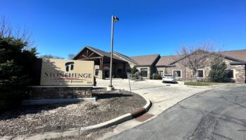 Exterior view of Stonehenge Rehabilitation Center entrance with stone facade, parking area, and directional signage