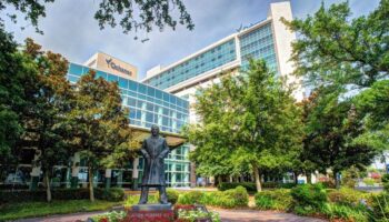Exterior view of Ochsner facility entrance with statue monument, landscaped grounds, and Ochsner building signage