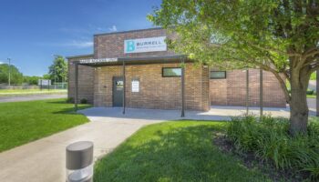 Exterior view of Burrell Behavioral Health Rapid Access Unit showing brick building facade, signage, landscaped grounds, and entrance walkway