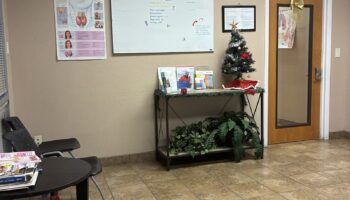 Interior reception area with informational displays, seating chairs, decorative plants, and educational materials on walls