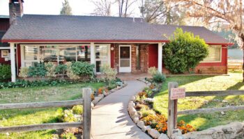 Exterior of red brick treatment facility building with white covered porch, landscaping, and wooden fencing
