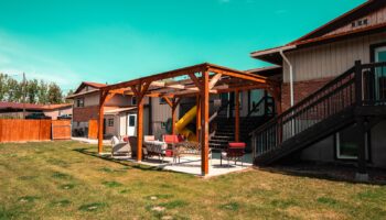 Exterior covered patio with wooden pergola, seating areas, and fire pit for outdoor gathering and recreation