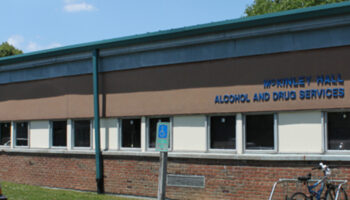 Exterior brick building showing McKinley Hall Alcohol and Drug Services signage with green metal roof overhang