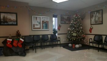 Interior waiting room with black seating chairs, decorated Christmas tree, holiday garland, and framed wall art