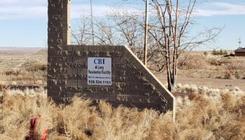 Exterior view of CBI Al Long Residential Facility stone sign with address and phone number on desert landscaping