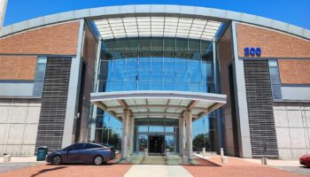 Exterior view of modern medical center building with brick and glass architecture, covered entrance portico, and clear blue sky