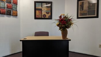 Interior office with desk, office chair, framed artwork, and floral arrangement decoration