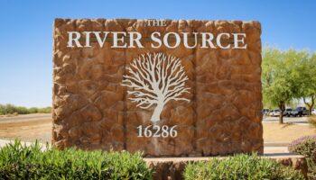 Exterior monument sign reading 'The River Source' with white tree logo and address number in desert landscaping