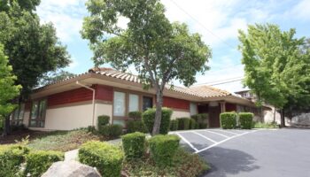 Exterior view of treatment center with red brick accents, landscaped grounds, and main entrance with parking area