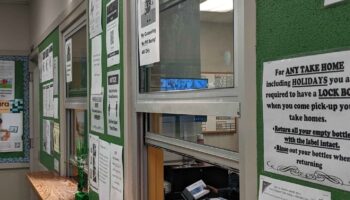 Interior view of medication dispensary with service counter and operational information posted on wall