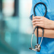 A doctor in scrubs holds a stethoscope. Learn about whether Blue Cross Blue Shield (BCBS) provides rehab coverage, here.