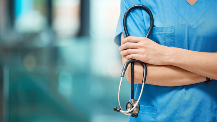 A doctor in scrubs holds a stethoscope. Learn about whether Blue Cross Blue Shield (BCBS) provides rehab coverage, here.