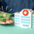 A small, model hospital next to some fake money. Does Kaiser Permanente offer drug detox or rehab coverage? Learn more here.