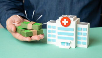 A small, model hospital next to some fake money. Does Kaiser Permanente offer drug detox or rehab coverage? Learn more here.